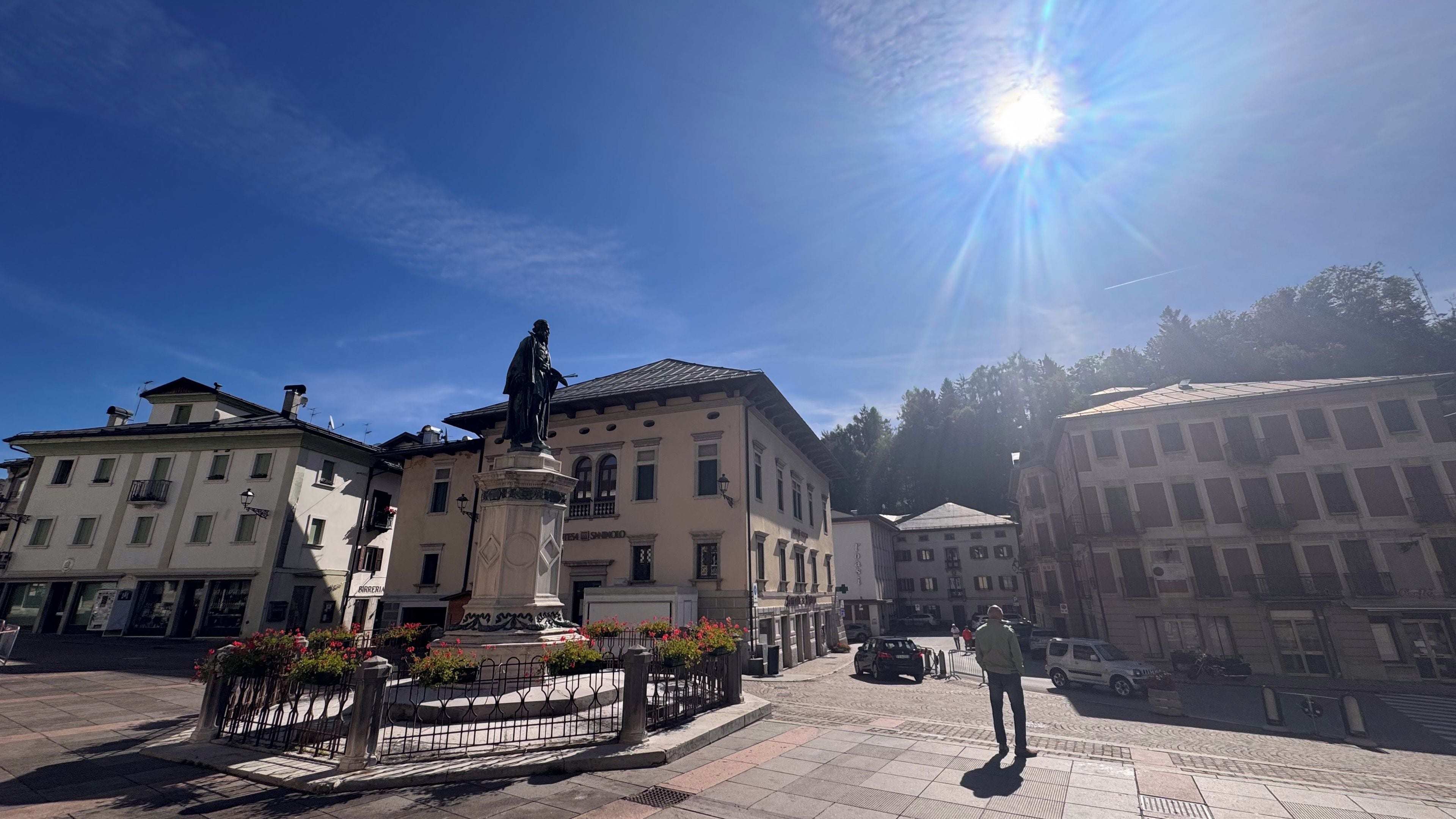 Une place avec une statue, des bâtiments et un ciel dégagé.
