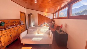 A cozy interior with a sofa, wooden cabinets, and a dining area with a table set for two. - Residenza Marmarole by Ca-sa Check (Pieve di Cadore)