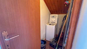 A compact bathroom with a white toilet, a small trash bin, and a vacuum cleaner. - Residenza Marmarole by Ca-sa Check (Pieve di Cadore)