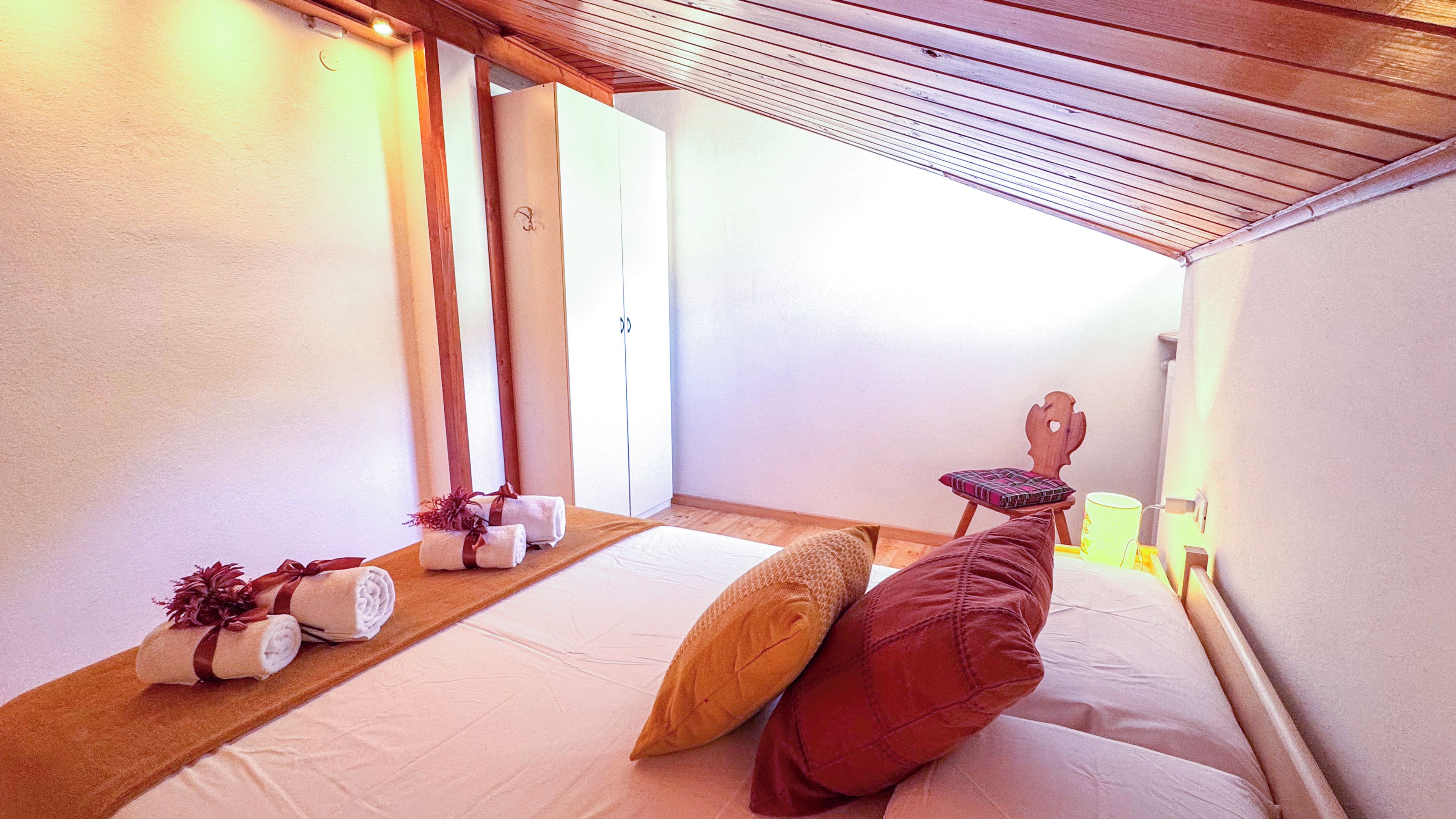 Une chambre d’hôtel avec un lit, des oreillers, une tête de lit en bois, une table de chevet et un miroir.