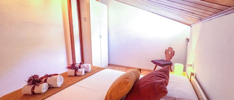 Una habitación de hotel con cama, almohadas, cabecero de madera, mesita de noche y espejo.