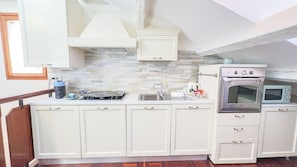 A compact kitchen with white cabinets, a built-in oven, a microwave, and a sink.