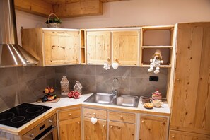 Eine Küche mit Holzschränken, einem Edelstahl-Spülbecken und einem eingebauten Backofen.