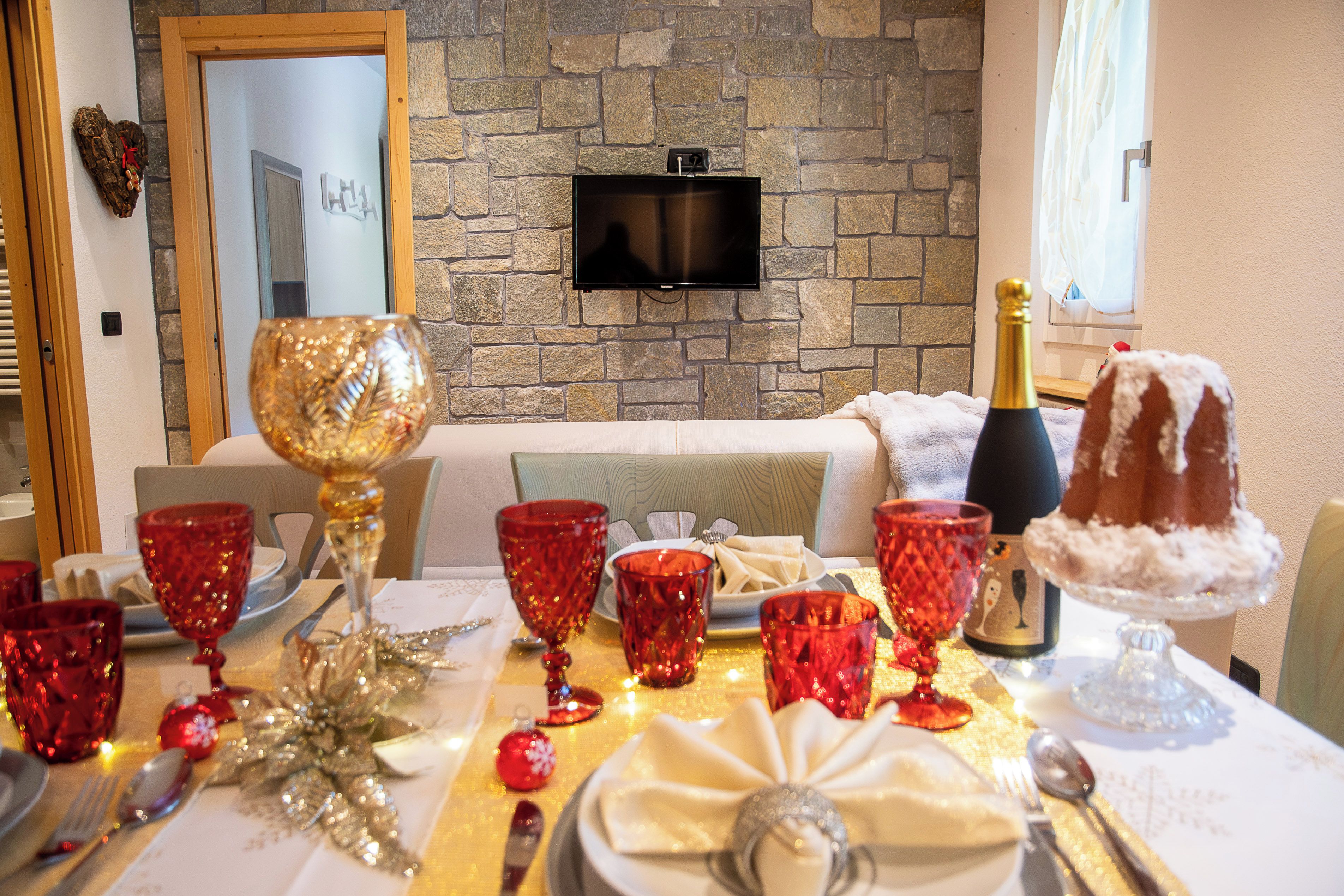 A dining table set with red glassware, a cake, and a bottle of champagne.