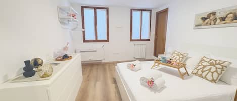 Un dormitorio con cama, mesita de noche y ventana.