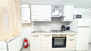 A modern kitchen with white cabinets, a gas stove, a built-in oven, a microwave, and a coffee maker. - Sweet Apartment by Ca-sa Check (Chioggia)