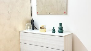 A minimalist room with a white dresser, a framed mirror, and decorative items including a vase and a candle holder. - Sweet Apartment by Ca-sa Check (Chioggia)