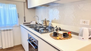 Een moderne keuken met een gasfornuis, een waterkoker en een koffiezetapparaat op het aanrecht.