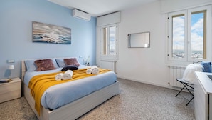 Quarto com cama, janela, radiador e vista da cidade.