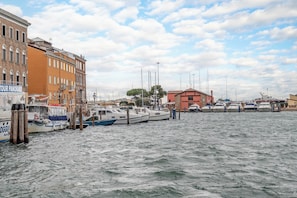 Un puerto deportivo con barcos amarrados, edificios al fondo y cielo despejado.