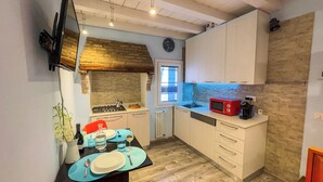 A compact kitchen with a gas stove, a red microwave, and a sink. - La Casa Gialla by Ca-sa Check (Chioggia)