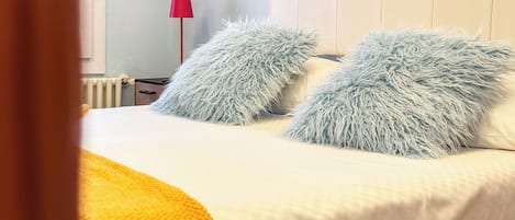 A neatly made bed with fluffy pillows and a yellow throw blanket.