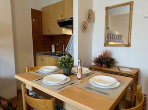 A dining area with a wooden table set for four, a small potted plant, and a bottle of water. - Maison Letì Ca-sa Check (Aprica)