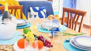 Una mesa de comedor dispuesta con platos, vasos, una botella y frutas.