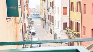Uma rua estreita com edifícios em ambos os lados, um carro estacionado e um barco ao fundo.