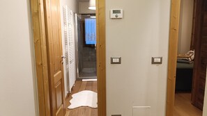 Ein Flur mit Holztüren, einem weißen Heizkörper, einem Thermostat und einem Lichtschalter an der Wand.