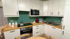 A compact kitchen with white cabinets, a microwave, a kettle, and a coffee maker. - Casa Mia by Ca-sa Check (Aprica)