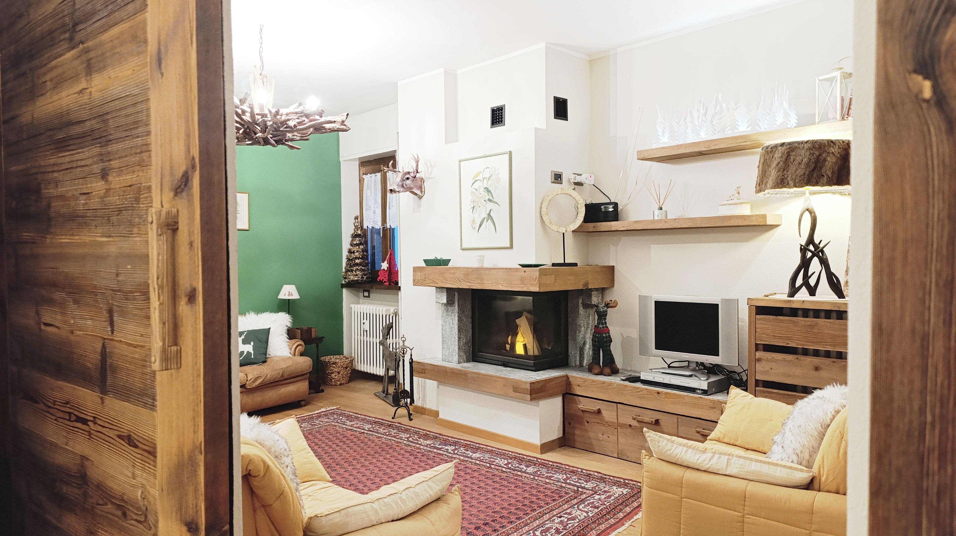Een gezellige woonkamer met een open haard, houten meubels en decoratieve objecten.