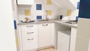 A compact kitchen with white cabinets, a stainless steel sink, and a compact refrigerator. - Appartamento Sestiere Castello by Ca-sa Check (Venice)