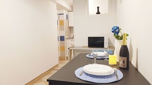 A dining area with a table set for two, a laptop, a vase with a blue flower, and a bottle of wine. - Appartamento Sestiere Castello by Ca-sa Check (Venice)