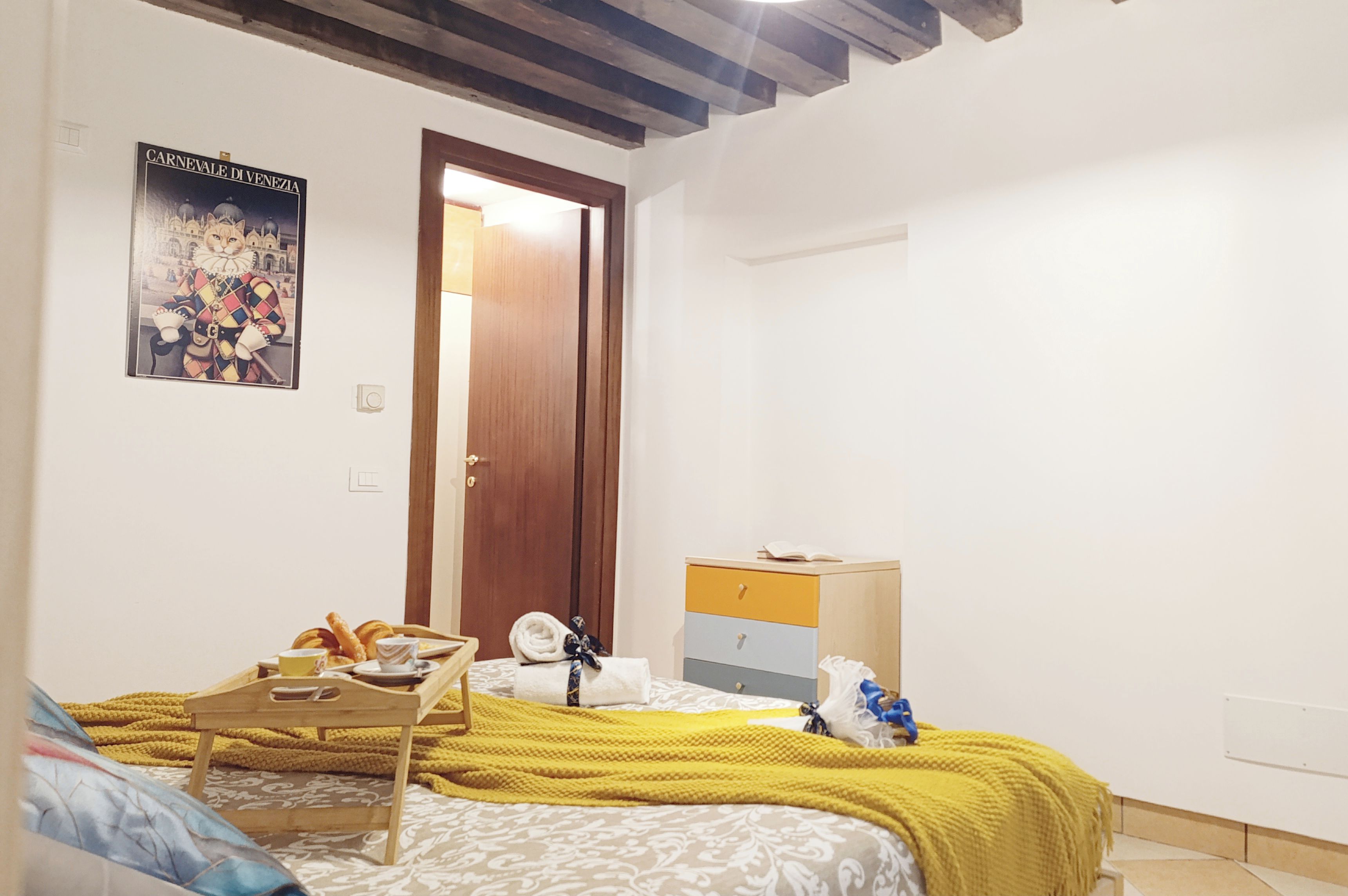 Una camera da letto con un letto, un comodino di legno con articoli per la colazione, un armadio e un quadro appeso al muro.