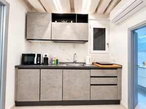 Eine moderne Küche mit grauen Schränken, einer Mikrowelle, einer Kaffeemaschine und einem Fenster über der Spüle.