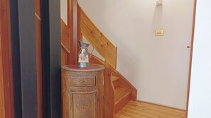 Una escalera de madera con un contenedor metálico sobre una pequeña mesa al pie.