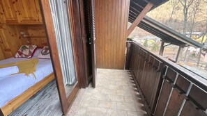 A wooden balcony with a bed and a window. - Coccola Alpina by Ca-sa Check (Aprica)