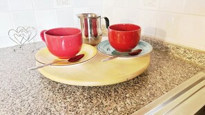 A kitchen counter with two red cups on saucers, a metal pitcher, and a spoon. - Coccola Alpina by Ca-sa Check (Aprica)