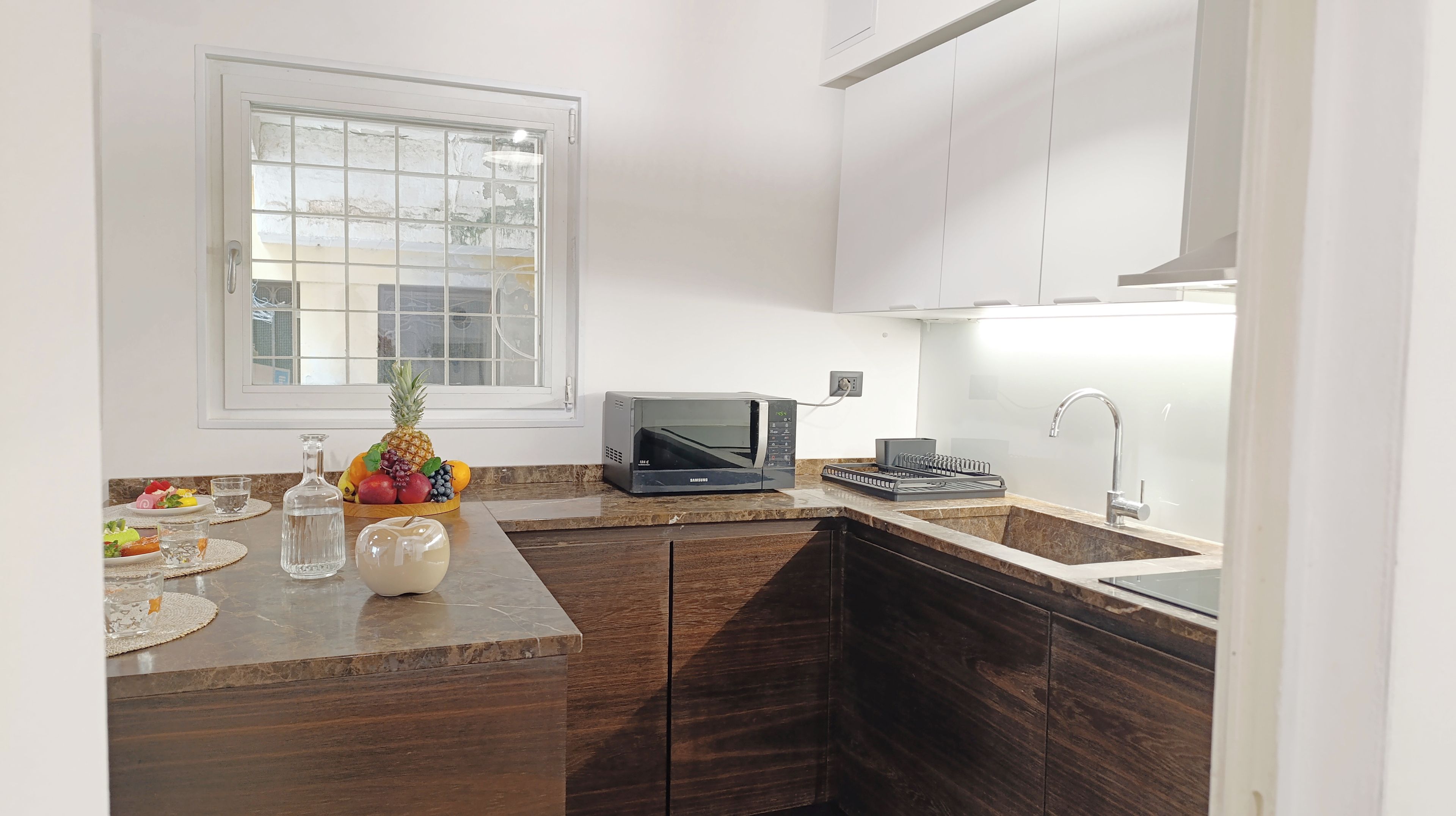 A modern kitchen with a microwave, sink, and window.