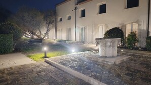 Um pátio com um banco de pedra, um vaso de plantas e um edifício com várias janelas.