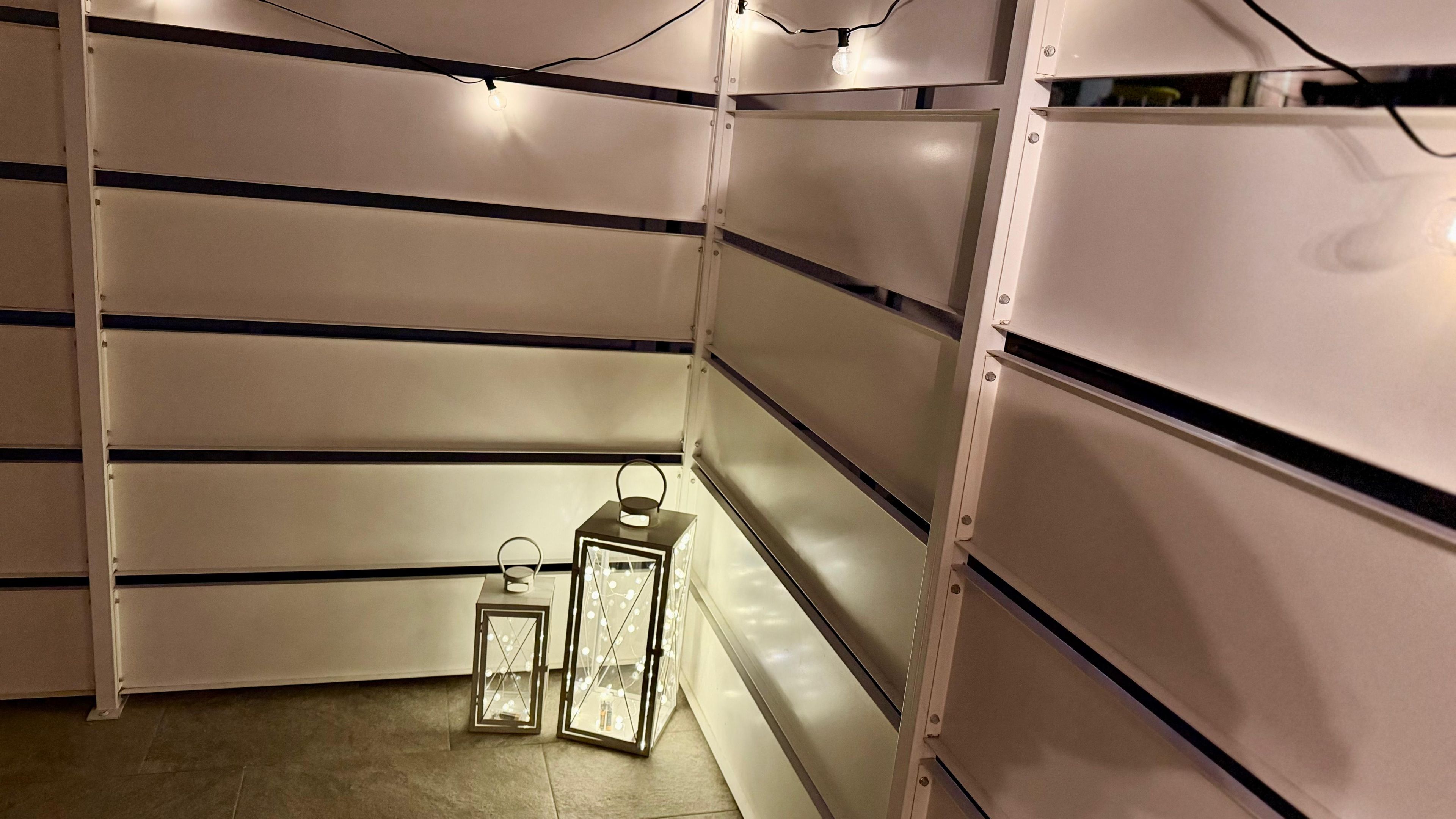 Um depósito com estantes de metal, piso de azulejos e duas lanternas iluminadas.