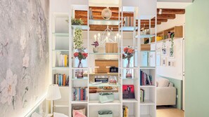 Ein modernes Interieur mit Bücherregal, Küche und Sitzgelegenheit.