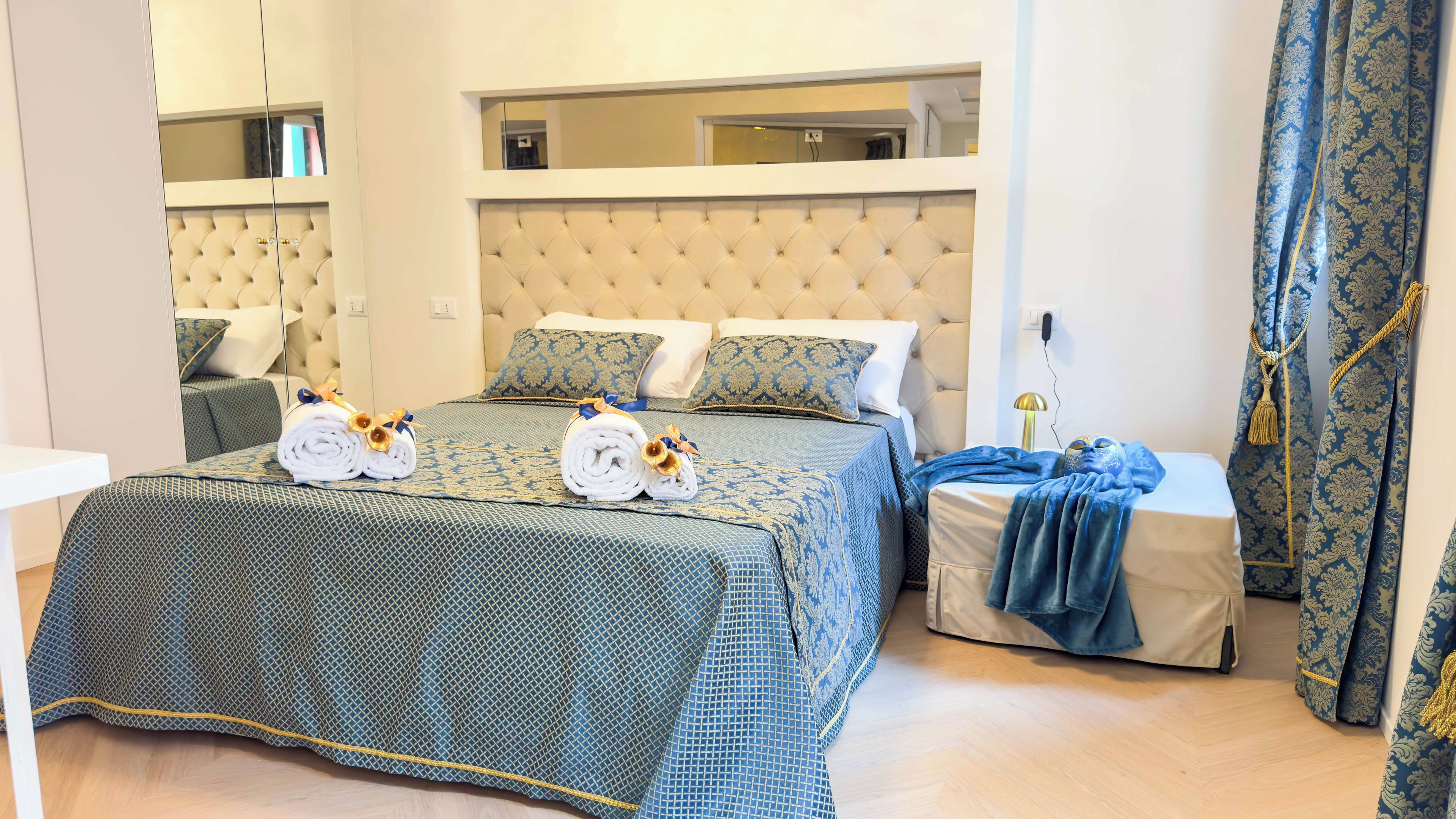 Ein Hotelzimmer mit einem großen Bett, einer Schlafcouch, einem Nachttisch und einem Spiegel.