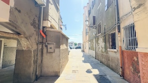 A narrow urban street with buildings on either side, a clear sky, and a few parked cars. - Suite Palazzo Ravagnan by Ca-sa Check (Chioggia)