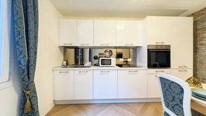 A compact kitchen with white cabinets, a microwave, a kettle, and a stove. - Suite Palazzo Ravagnan by Ca-sa Check (Chioggia)