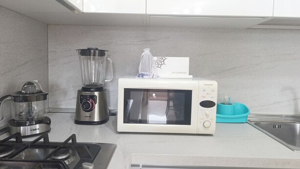 Una cocina con estufa a gas, licuadora, microondas y hervidor.