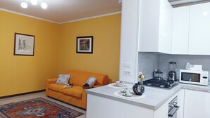 Una cocina compacta con estufa, microondas y hervidor.
