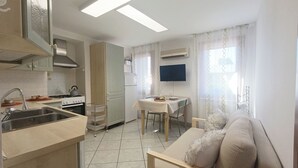 A compact kitchen with a sink, stove, and a dining area with a table and chairs. - Mi Casa Es Tu Casa by Ca-sa Check (Chioggia)