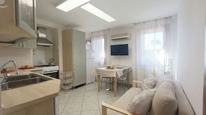 A compact kitchen with a sink, stove, and a dining area with a table and chairs. - Mi Casa Es Tu Casa by Ca-sa Check (Chioggia)