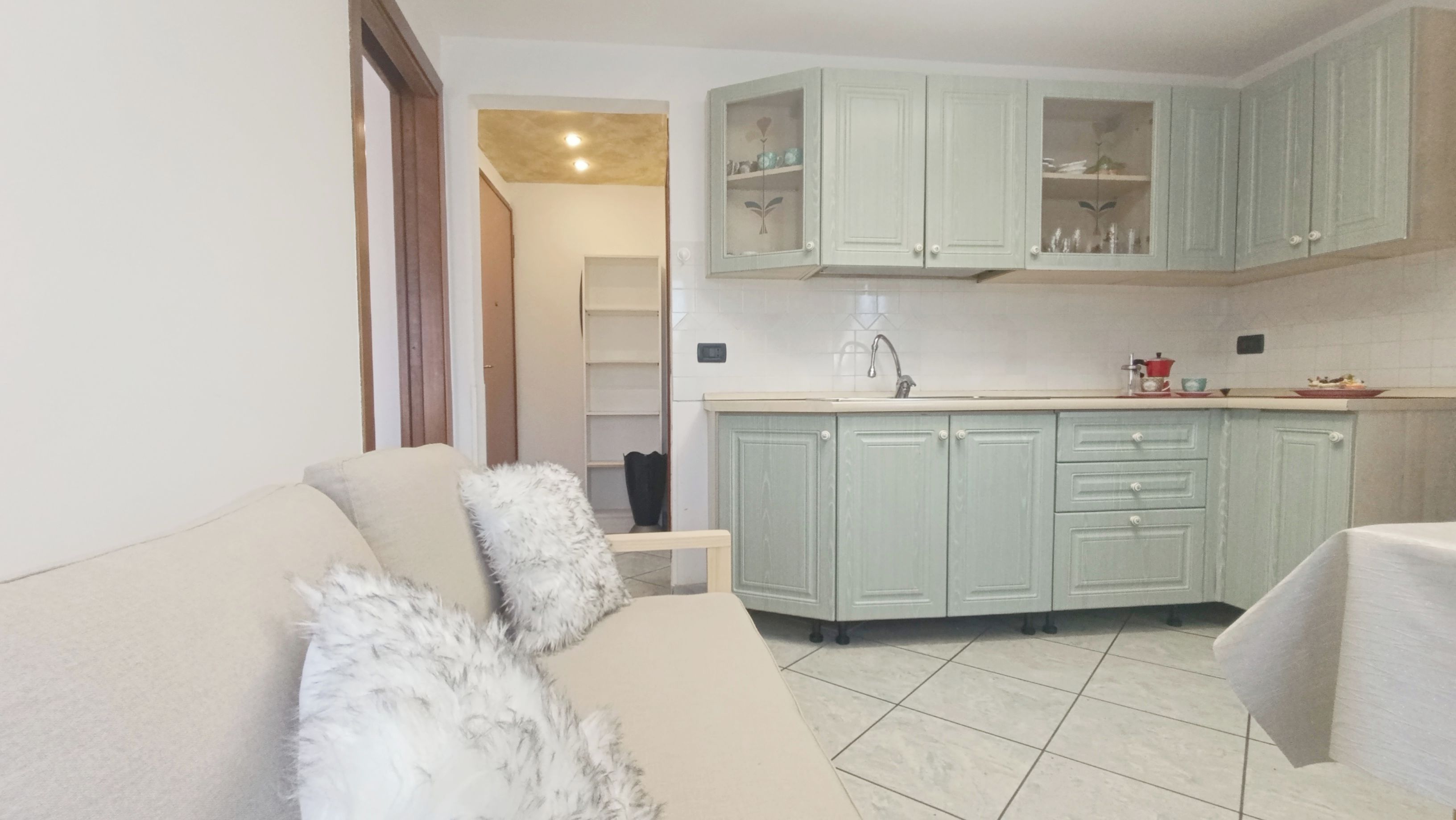 A living room with a sofa and a dining area with a kitchen in the background.