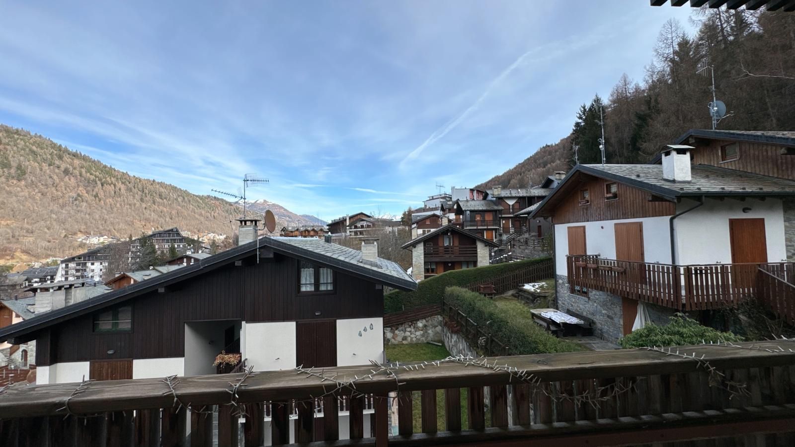 A mountain village with traditional wooden houses, a clear sky, and a view of the surrounding hills.