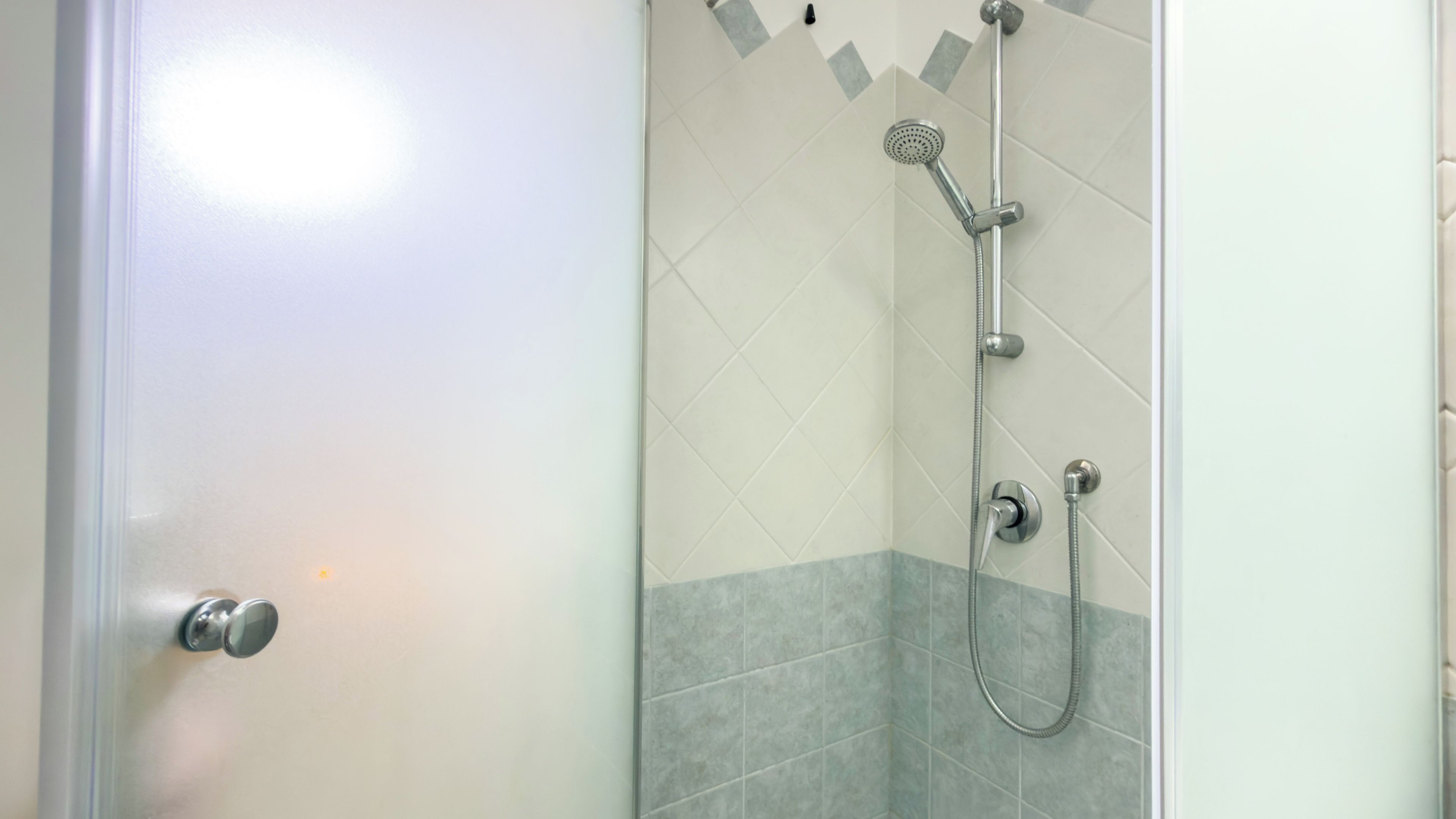Une salle de bain avec une douche, une porte et des murs carrelés.