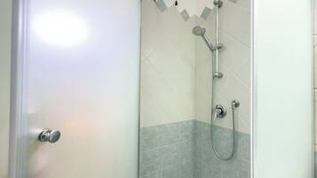 Une salle de bain avec une douche, une porte et des murs carrelés.
