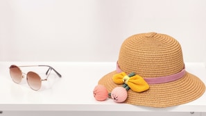 A straw hat with a wide brim and a decorative bow, placed next to a pair of sunglasses on a white surface. - Code Zero Apartment by Ca-sa Check (Chioggia)