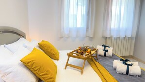 Ein Hotelzimmer mit einem Bett, Kissen, einem Tablett mit Speisen und Getränken sowie Handtüchern.