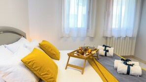 A hotel room with a bed, pillows, a tray with food and drinks, and towels. - Code Zero Apartment by Ca-sa Check (Chioggia)