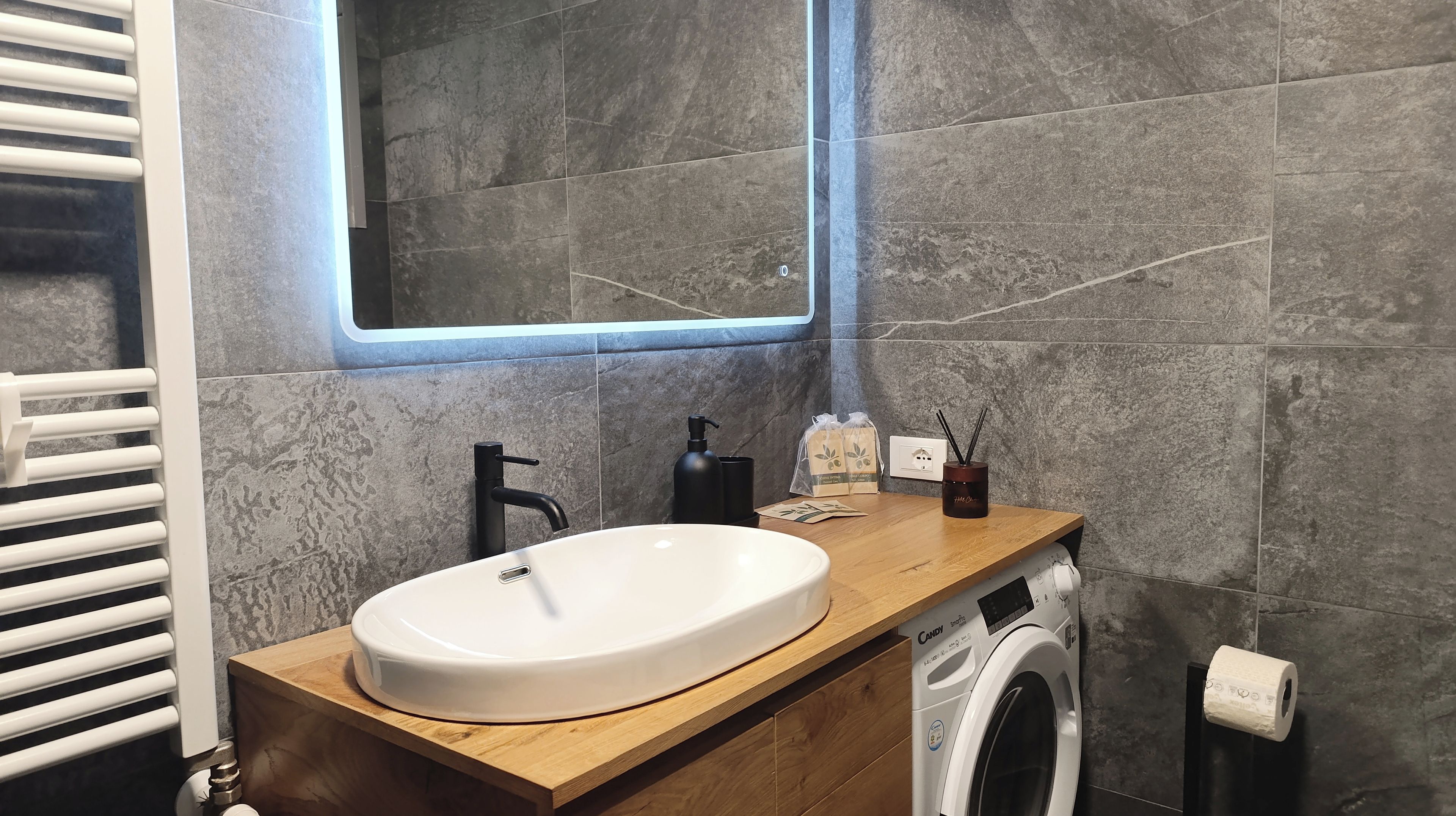 A bathroom with a white sink, black faucet, wooden countertop, and a built-in washing machine.