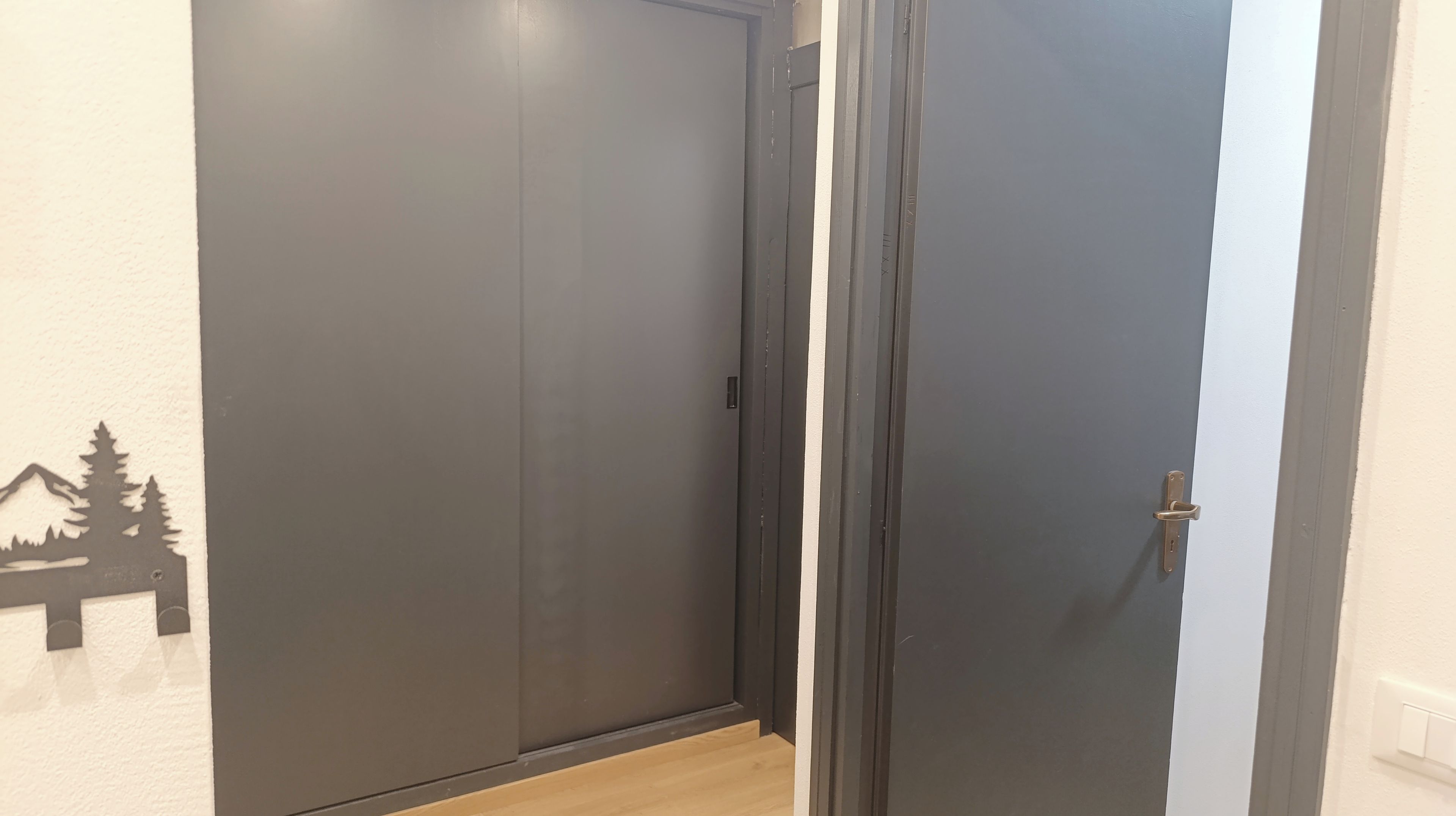 Ein Flur mit einer geschlossenen Tür und einer Wand mit Bergkonturen.