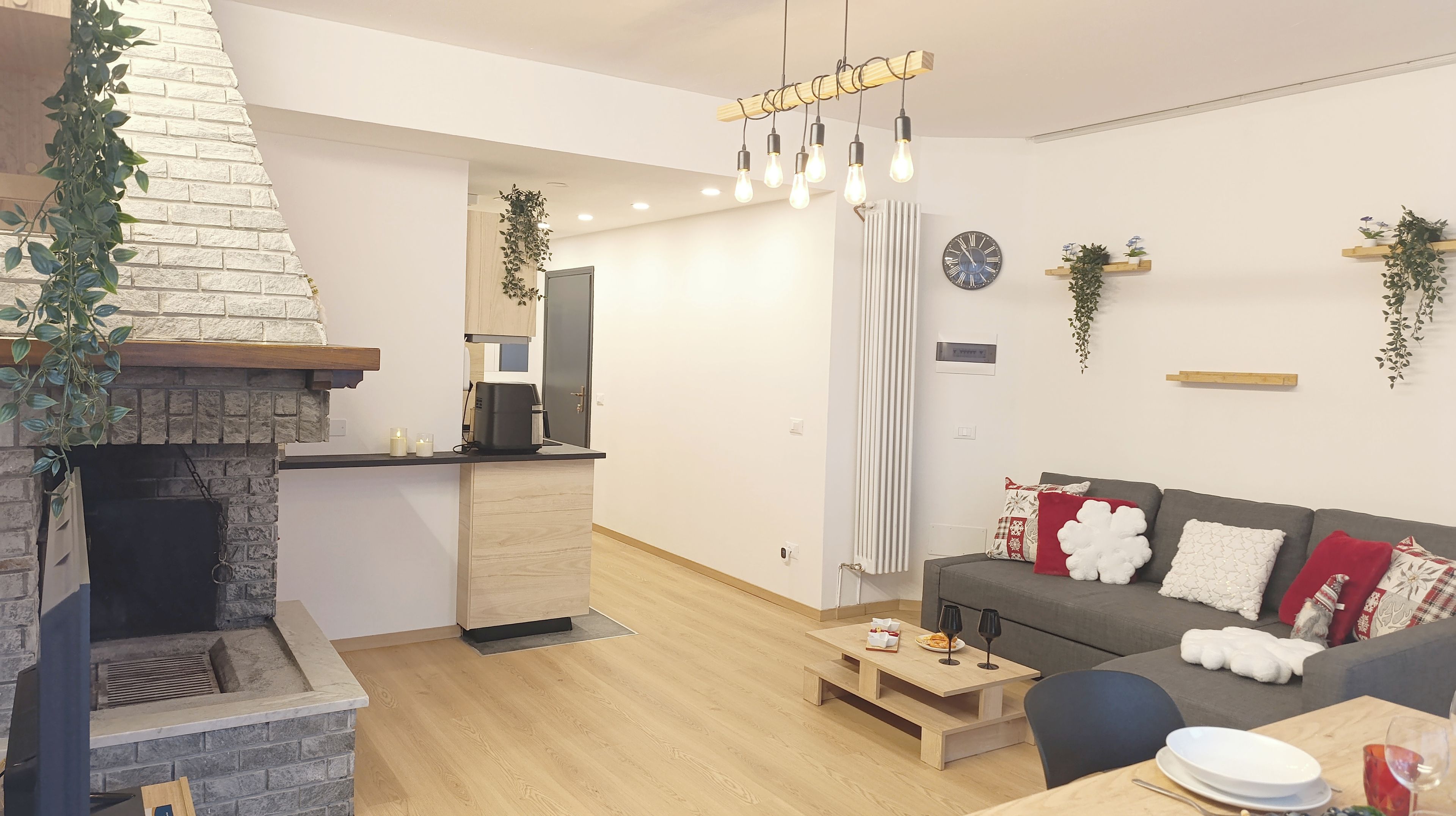 A modern living room with a fireplace, a sofa with decorative pillows, a coffee table, and a dining table set for two.